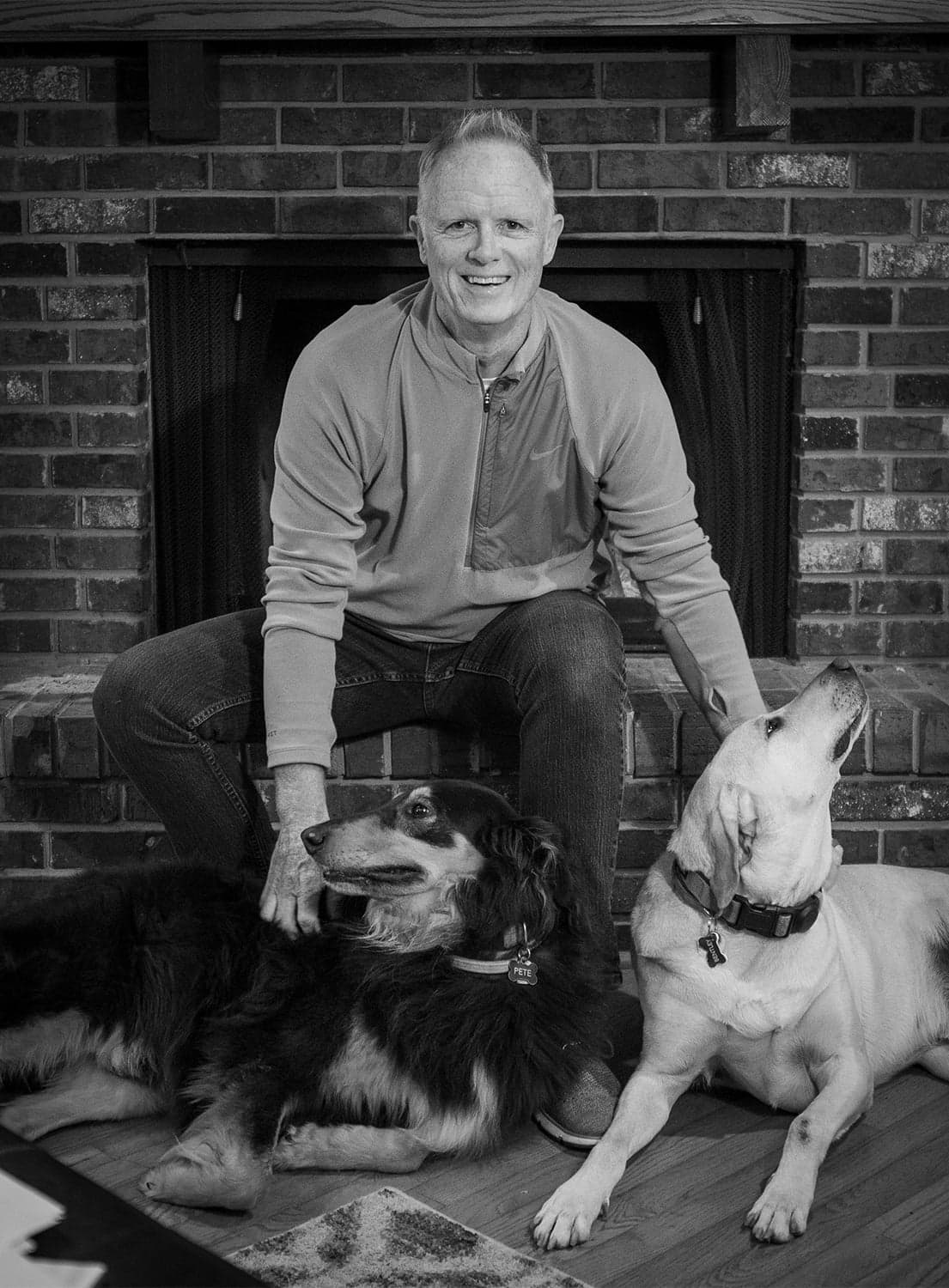Chris Huelat with his dogs Pete and Tucker by the fireplace